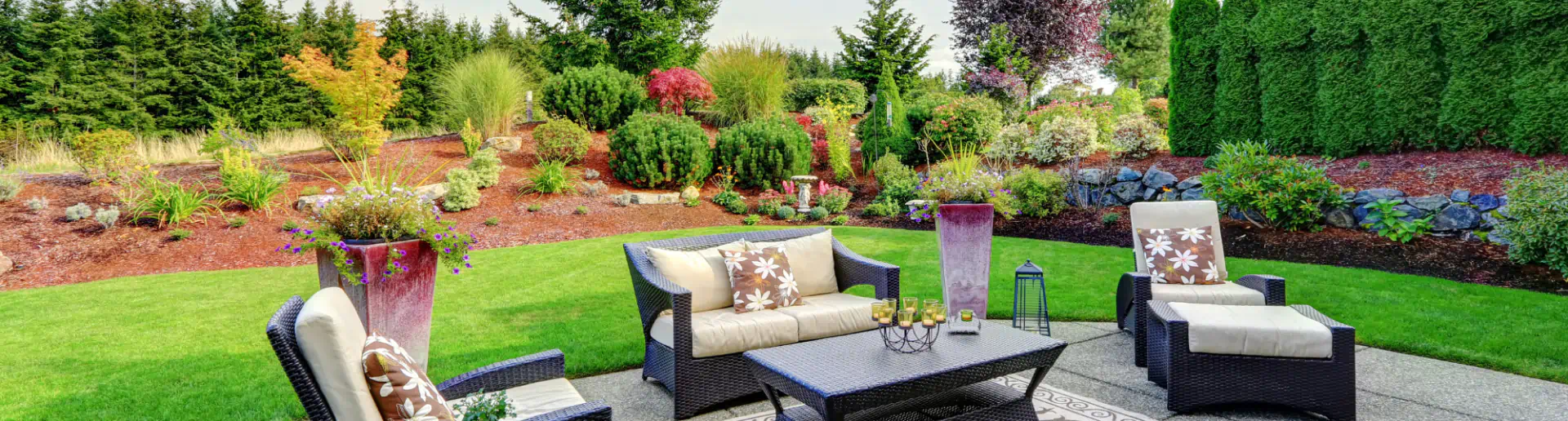outdoor space with some grey sofas and grass bushes around